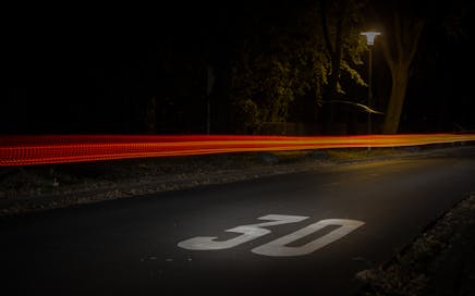 A long exposure night street scene in Mönchengladbach showcasing vibrant car light trails.