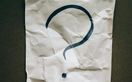 A crumpled sheet with a large black question mark on a dark background.