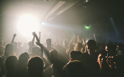 A lively nightclub with people dancing and enjoying music under colorful lights.