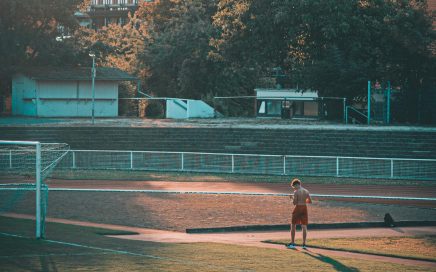 A person training on an athletic field in Wiesbaden, Germany during daytime with buildings in the background.