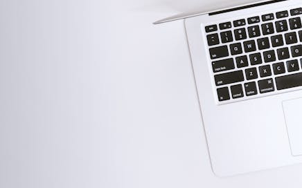 Aerial view of a sleek laptop keyboard on a clean, white surface, ideal for tech backgrounds.