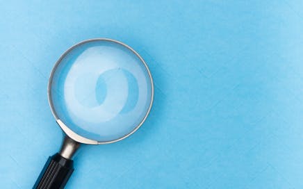 Close-up of a magnifying glass on a blue surface, ideal for search and exploration themes.