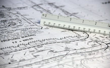 Detailed close-up of architectural blueprints with scale ruler, showing building plans and measurements.