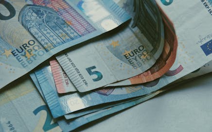 Detailed close-up of various Euro banknotes on a white surface, perfect for finance-related content.